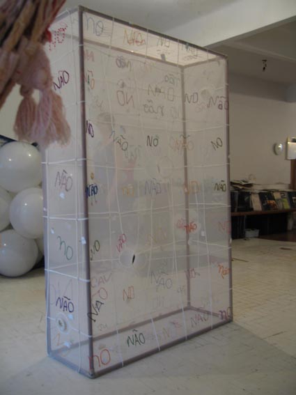 photograph of Ernesto Neto's fabric sculpture, Nao/No, made in collaboration with the weavers' collective Coopa-Roca. A rectangular box made from white fabric with the words 'nao' and 'no' written over it in black marker 