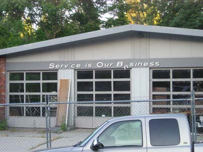 photograph of abandoned gas station with sign that reads Service is Our Business 